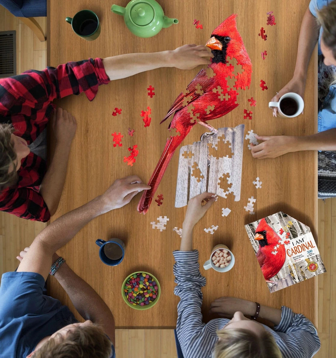 People around a wooden table with a red cardinal bird, coffee cups, and a puzzle.
